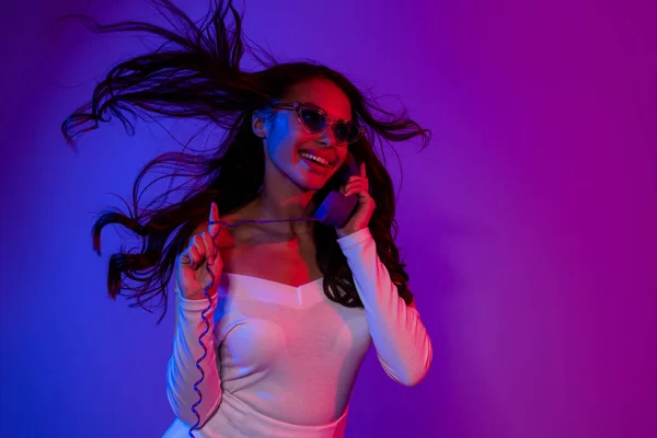 Foto wanita cantik berambut cokelat Milenial mengatakan telepon memakai kacamata gaun putih terisolasi dari latar belakang warna neon — Stok Foto