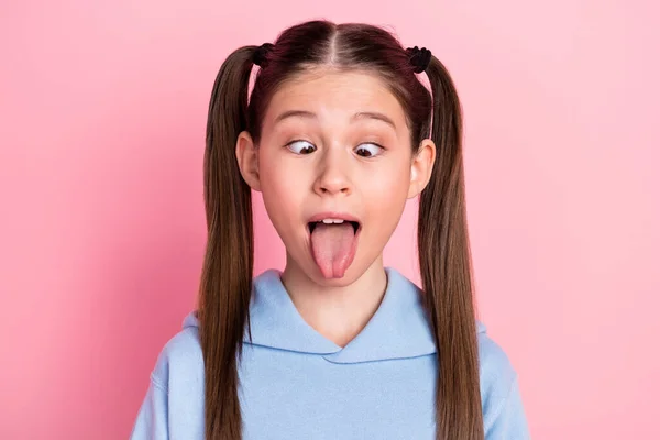 Photo portrait of funny schoolgirl showing tongue fooling grimacing isolated on pastel pink color background — Stockfoto