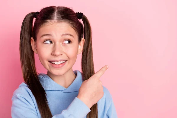 Foto retrato de colegiala curiosa mostrando el dedo vacío sonriendo aislado sobre fondo de color rosa pastel —  Fotos de Stock