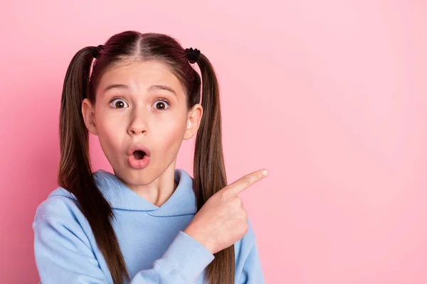 Photo portrait of surprised schoolgirl showing finger copyspace promoting isolated on pastel pink color background — стоковое фото