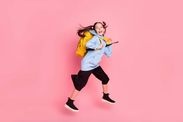 Foto de tamaño corporal de longitud completa de la chica saltando con la mochila amarilla que va a la escuela aislado pastel fondo de color rosa —  Fotos de Stock