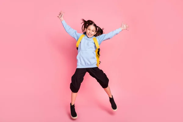 Взгляд в полный рост на прекрасную жизнерадостную девочку, которая весело прыгает на розовом фоне. — стоковое фото