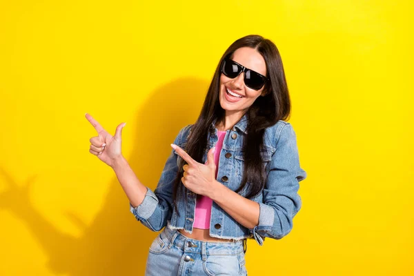 Foto de alegre agradable impresionante mujer joven usar gafas de sol fresco dedo vacío espacio aislado en el fondo de color amarillo —  Fotos de Stock