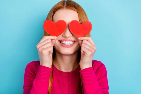 Photo of funky shiny young woman wear pink shirt two red hearts cover eyes smiling isolated blue color background — Fotografia de Stock