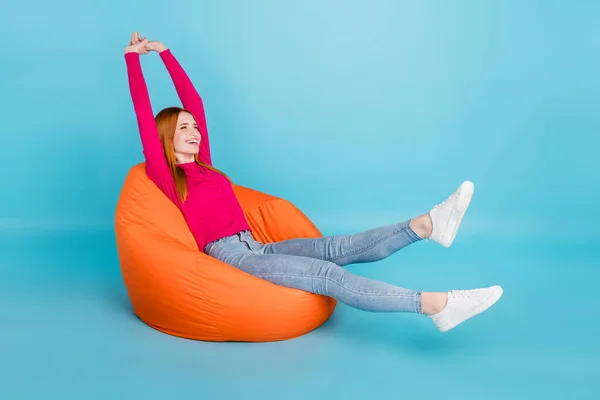 Full length photo of adorable sweet woman wear pink shirt sitting beanbag stretching smiling isolated blue color background — Fotografia de Stock
