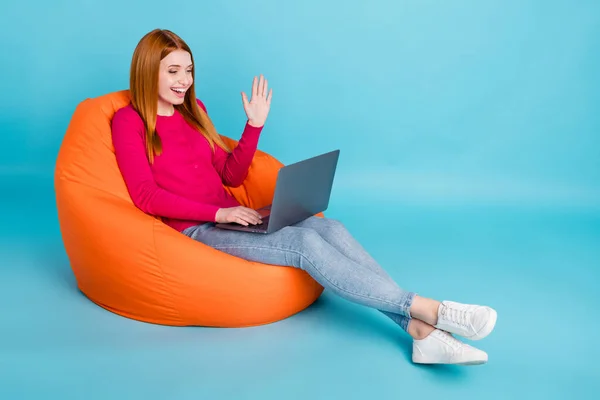 Foto panjang lengkap dari wanita muda yang menawan manis mengenakan kemeja merah muda duduk beanbag berbicara gadget modern terisolasi biru latar belakang warna — Stok Foto