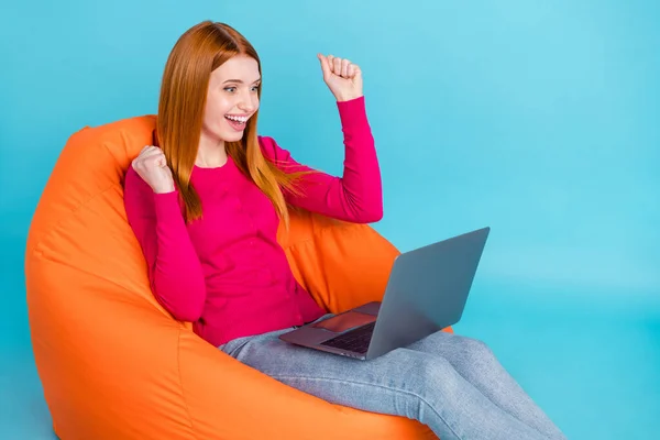 Profil foto av Hurra unga räv hår dam ser laptop sitta på väska bära rosa tröja jeans isolerad på blå bakgrund — Stockfoto