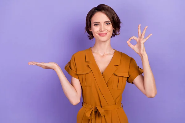 Foto de mujer joven feliz sonrisa positiva de la mano muestra producto promocional bien retroalimentación aislado sobre fondo de color violeta —  Fotos de Stock