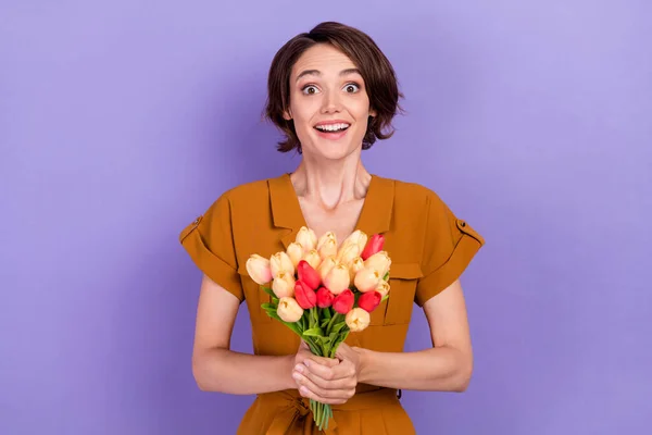 Heyecanlı genç bir kadının fotoğrafı. Mutlu bir gülümseme sürprizi. Çiçek buketini mor arka planda izole et. — Stok fotoğraf