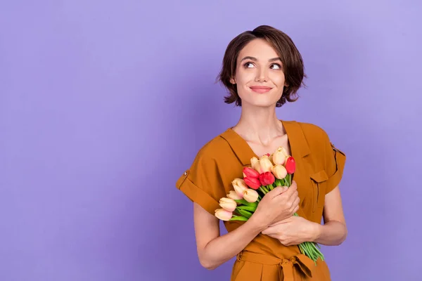 Φωτογραφία της νεαρής γυναίκας χαρούμενο θετικό χαμόγελο ονειρικό μπουκέτο λουλούδια παρουσιάζουν απομονωμένα σε μωβ φόντο χρώμα — Φωτογραφία Αρχείου