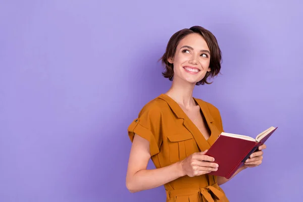 Fénykép boldog álmodozó vidám fiatal nő fogja a kezét könyv olvasó néz üres tér elszigetelt lila színű háttér — Stock Fotó