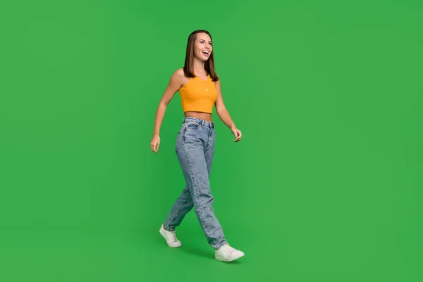 Foto de cuerpo completo de la joven dama morena impresionada ir a ver llevar top jeans zapatos aislados en el fondo de color verde — Foto de Stock