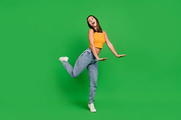 Foto de cuerpo completo de la joven divertida dama morena danza usar pantalones vaqueros zapatos aislados en el fondo de color verde —  Fotos de Stock