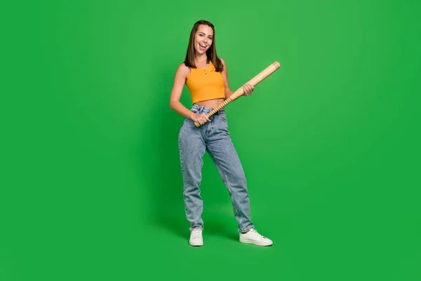 Full body photo of young cool brunette lady hold bit wear top jeans shoes isolated on green color background — Stockfoto