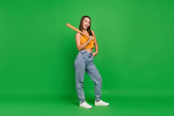 Full body photo of young positive cheerful woman hold hands bat smile isolated on green color background — Stockfoto