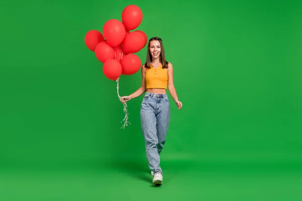 Largura completa foto de la joven feliz mujer alegre cogida de la mano globos venta paseo aislado sobre fondo de color verde — Foto de Stock