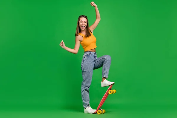 Foto de larga duración de la joven alegre alegre mujer usar gafas paseo longboard aislado sobre fondo de color verde — Foto de Stock