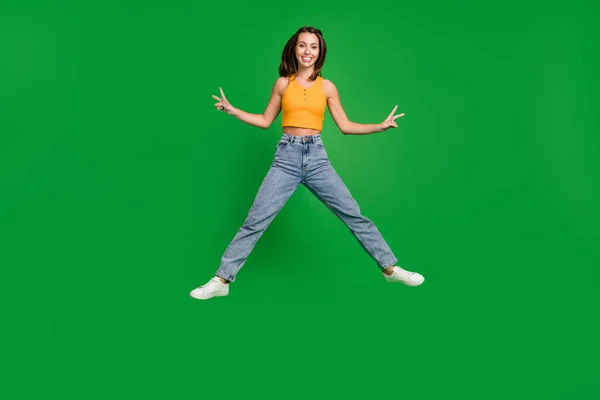 Full size photo of cheerful nice cool woman jump up make v-signs smile isolated on green color background — Stockfoto