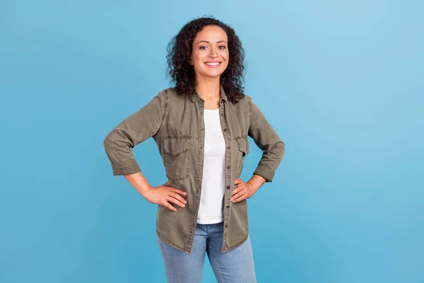 Portrait of attractive cheerful wavy-haired girl hands on hips isolated over bright blue color background — Fotografia de Stock