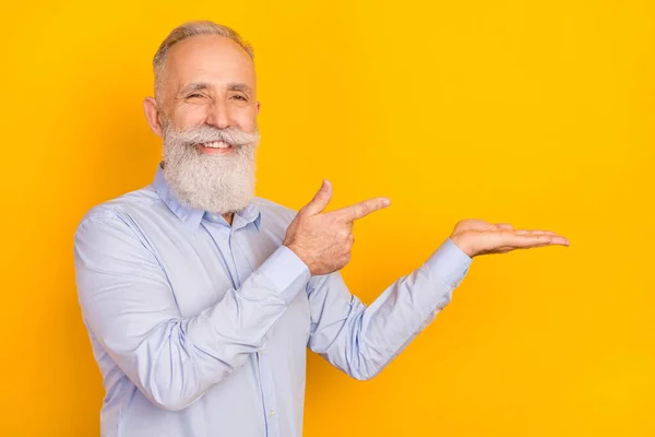 Retrato de atractivo hombre alegre de mediana edad sosteniendo en la palma demostrando espacio de copia anuncio aislado sobre fondo de color pastel gris — Foto de Stock