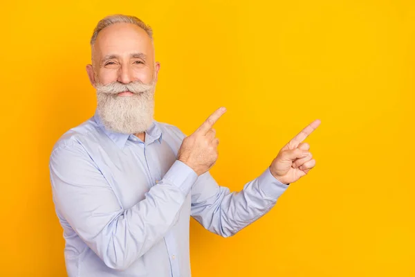 Photo of charming attractive old businessman point fingers empty space smile isolated on yellow color background — Stock Photo, Image