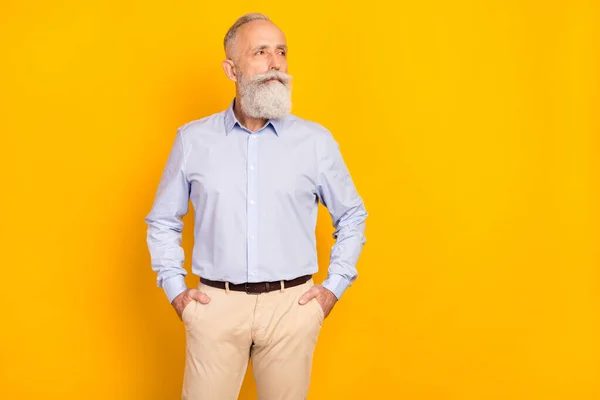 Foto de hombre encantador viejo soñador mirar espacio vacío sostener bolsillos de mano aislado om brillo amarillo color fondo — Foto de Stock