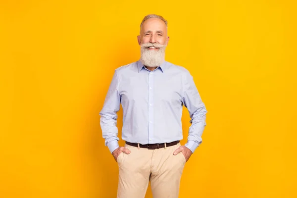Photo of attractive old happy man hold hands pocket smile good mood isolated on yellow color background — Stockfoto