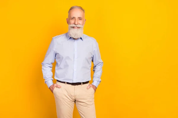 Photo of cheerful beard elder man stand wear blue shirt pants isolated on yellow color background — Stockfoto