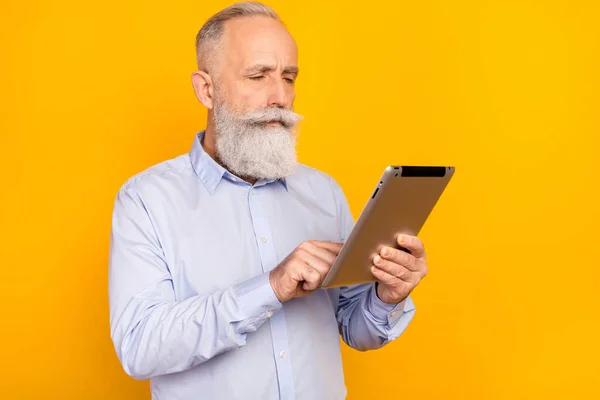 Photo de sérieux calme concentré vieil homme regard tenir tablette homme d'affaires isolé sur fond de couleur jaune — Photo