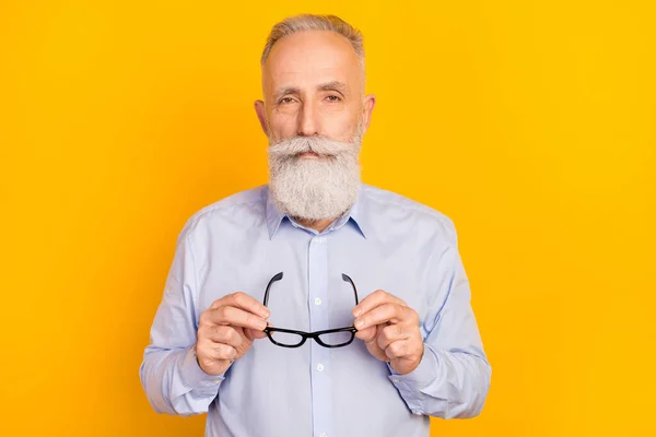 Foto de hombre viejo calmado serio cogido de la mano gafas desgaste formalwear camisa aislado sobre fondo de color amarillo — Foto de Stock