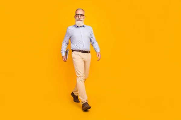 Pleine longueur photo de charme vieil homme aller bonne humeur tenir ordinateur portable sourire joyeux isolé sur fond de couleur jaune — Photo