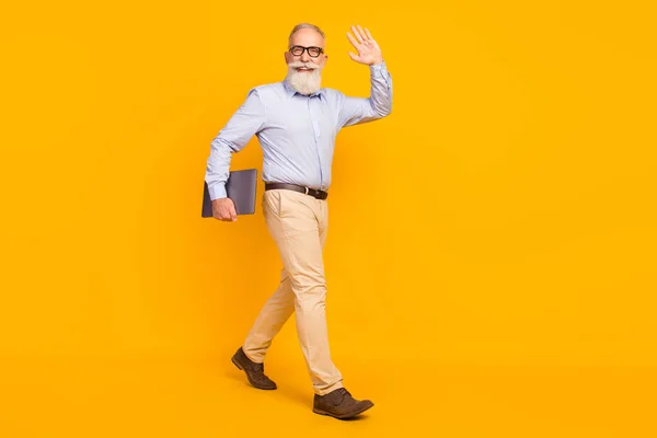 Full size photo of cheerful beard elder man hold laptop go wear spectacles blue shirt isolated on yellow color background — Fotografia de Stock