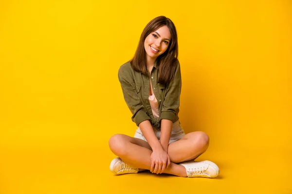 Photo of girl sit floor crossed legs look camera wear green shirt mini skirt sneakers isolated yellow color background.