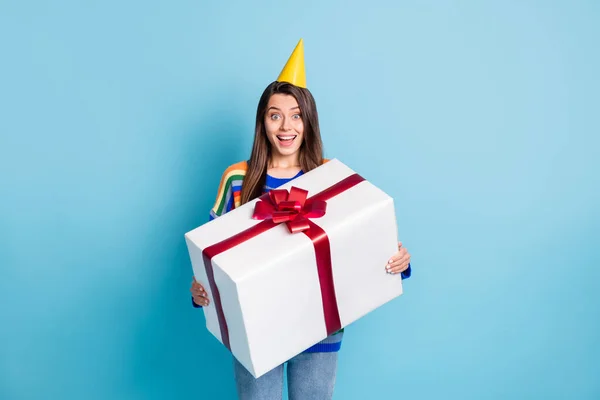 Photo d'adorable jeune femme heureuse tenir grand cadeau boîte porter cône anniversaire isolé sur fond de couleur bleue — Photo