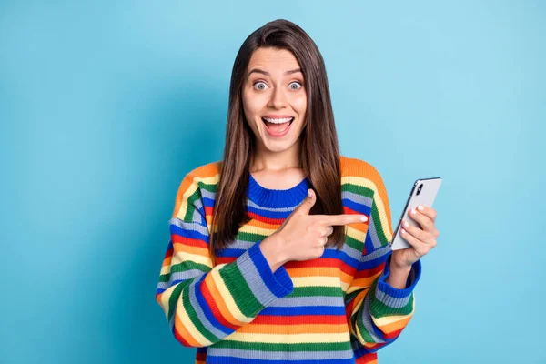 Portrait photo de fille étonné doigt pointant smartphone souriant en utilisant l'application isolée sur fond de couleur bleue vibrante — Photo