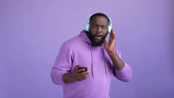 Energinen kaveri käyttää gadget kuulokkeet kuulla pop eristetty kirkas väri tausta — kuvapankkivideo