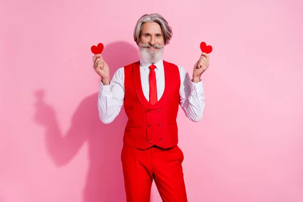 Portrait d'homme aux cheveux gris joyeux tenant dans les mains de petites cartes de coeur isolées sur fond rose pastel — Photo