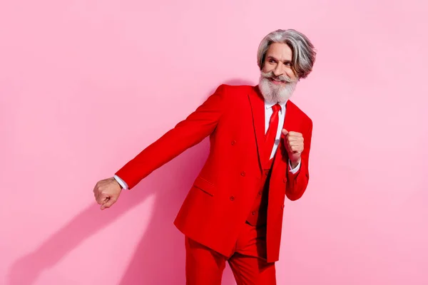Çekici, komik, emekli bir adamın fotoğrafı kırmızı takım elbise giyip boş bir alanda dans ederken çekilmiş pembe bir arka plan. — Stok fotoğraf