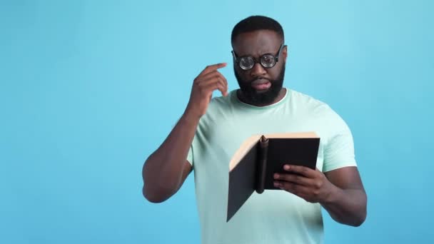 Orang yang tertekan membaca buku teks tidak mengerti tugas latar belakang warna biru yang terisolasi — Stok Video