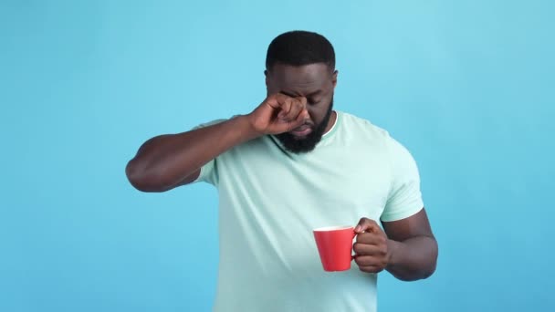 Guy wakker vroeg in de ochtend drinken latte geïsoleerde blauwe kleur achtergrond — Stockvideo