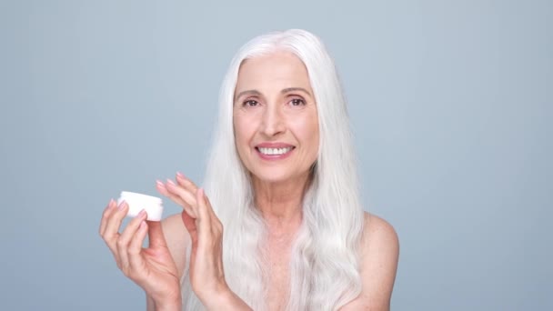 Pensioner retired lady use gel mask isolated pastel color background — Vídeo de stock