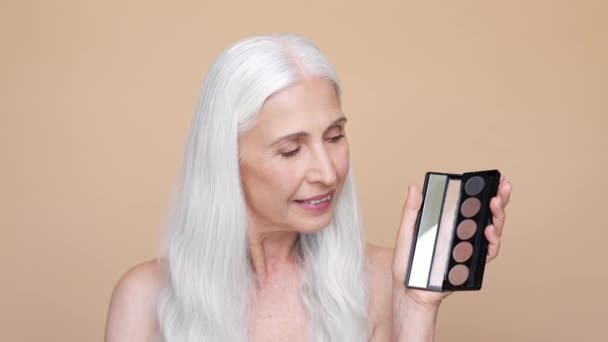 Pensionista jubilado señora uso paleta cepillo aislado color beige fondo — Vídeo de stock