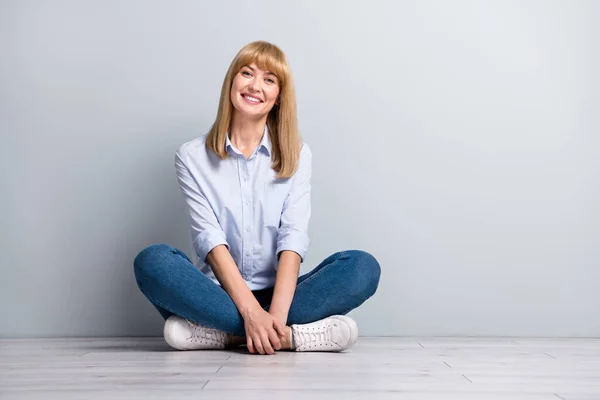 楽観的なフリーランスの女性の完全な長さ写真座っている床の足は グレーの色の背景に隔離されたリラックス会社の決定を渡り — ストック写真