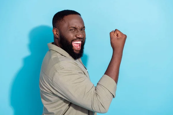 Foto del lado del perfil del joven africano emocionado celebrar el éxito ganar mano puño de lotería aislado sobre fondo de color azul — Foto de Stock