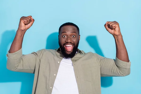 Photo of young cheerful african man rejoice fists hands champion ecstatic lottery isolated over blue color background — Stockfoto