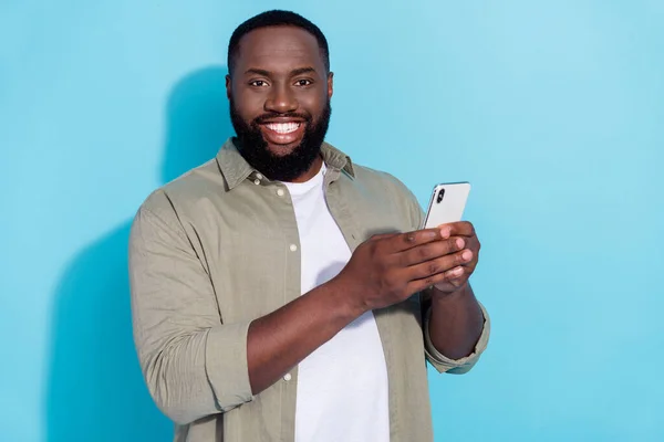 Foto de un hombre africano joven utilice el botón de descarga de la aplicación del teléfono inteligente repost aislado sobre fondo de color azul — Foto de Stock