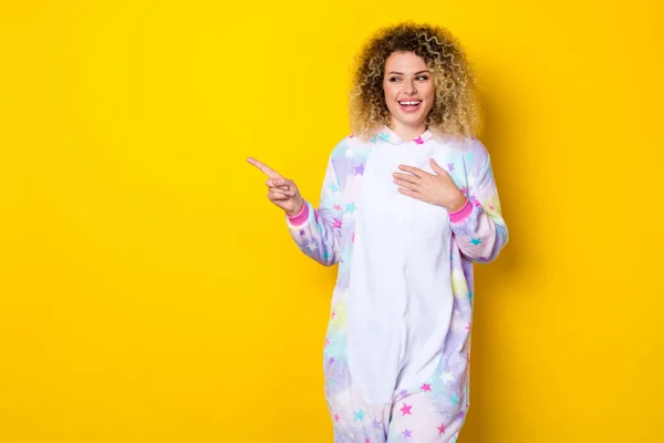 Retrato de chica atractiva de pelo ondulado alegre en pijama mostrando espacio en blanco copia riendo aislado sobre brillo amarillo color fondo — Foto de Stock