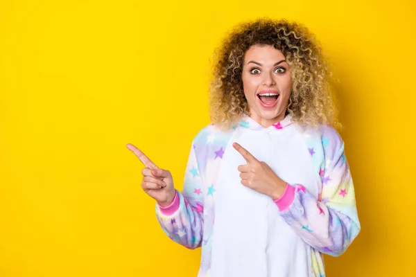 Portrait of attractive cheery stunned wavy-haired girl in pajama demonstrating copy blank space isolated over shine yellow color background — Fotografia de Stock