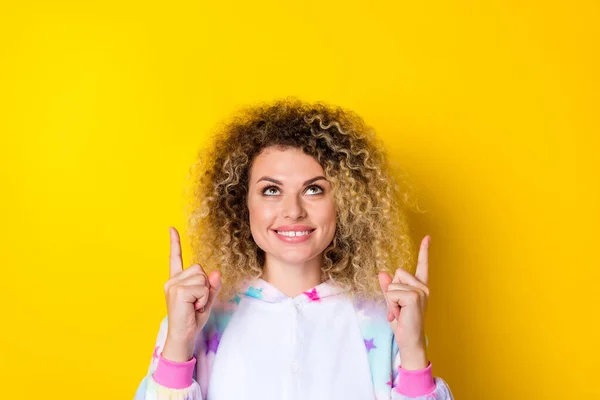 Portrait of attractive cheery wavy-haired girl in pajama demonstrating copy space ad look idea isolated over vivid yellow color background — Stok fotoğraf