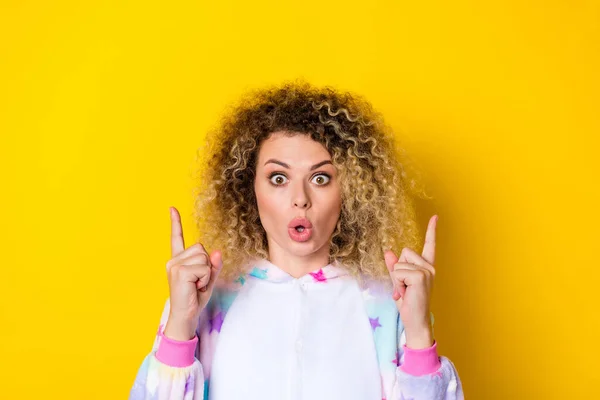 Portrait of attractive amazed wavy-haired girl in pajama demonstrating copy space new offer isolated over vivid yellow color background — Fotografia de Stock